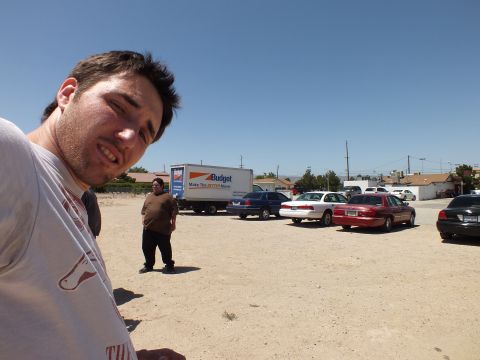 2003 Ford Crown Victoria - man poses close to the camera while a second stands by a Budget truck and a row of sedans