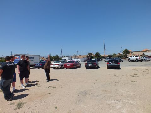 2003 Ford Crown Victoria - Men gather at the edge of a sandy lot, full-size sedans and trucks lined up across the gravel