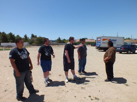 2003 Ford Crown Victoria - group of men converse on bare ground, one gesturing, a Budget box truck parked at the back