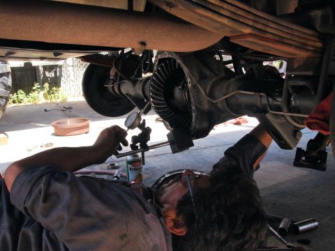 1994 Ford Bronco - A mechanic is shown working on the rear differential of a vehicle, using a dial indicator to measure gear backlash.