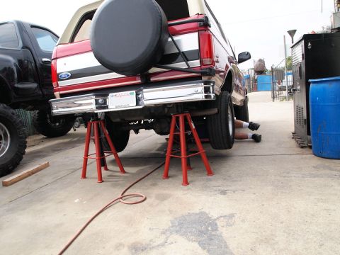 1994 Ford Bronco - A 1994 Ford Bronco is being worked on while supported by jack stands, with another vehicle visible.