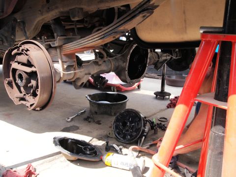 1994 Ford Bronco - The rear axle of a vehicle is disassembled with parts and tools laid out on the ground.