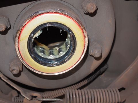 1994 Ford Bronco - Close-up view of a damaged wheel bearing seal, showing grease and the internal splines of the hub assembly.