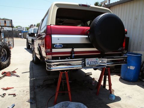 1994 Ford Bronco - Rear view of a Ford Bronco being worked on, with a spare tire mounted and a California license plate visible.