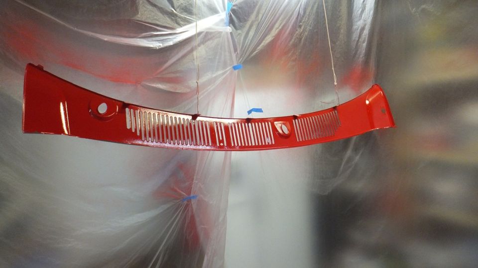 Red grille hanging, covered in plastic sheeting, with a Supermotors logo at the bottom right