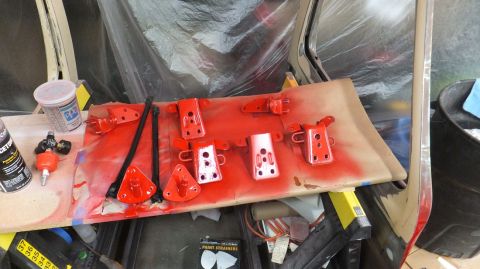 1983 Ford Bronco - Painting car door hinges and brackets red. Supplies include spray paint, a can of acetone, and paint strainers.