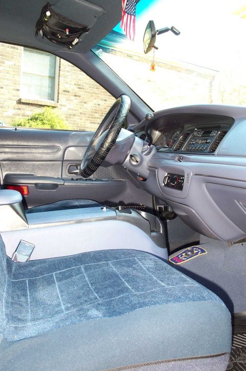 1998 Ford Crown Victoria - The interior of a car is shown, the dashboard, steering wheel, and seats, with an American flag visible.