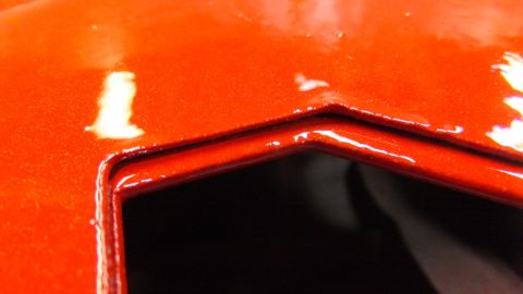 1983 Ford Bronco - Close-up of an orange automotive part showing a recessed edge and reflective surface.