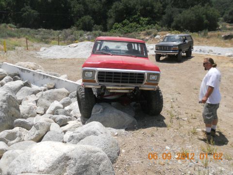 1986 Ford Bronco - A red Ford Bronco is shown off-road, with another Bronco in the background.