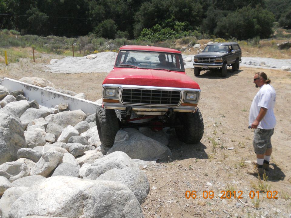 Red Ford Bronco with lifted suspension navigating large rocks