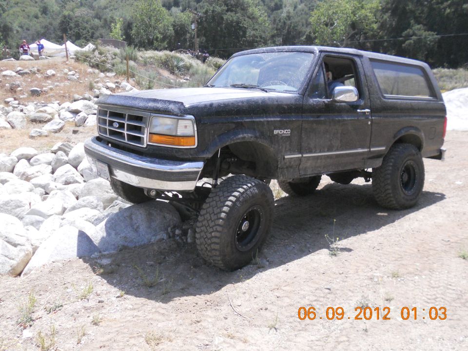 Black Ford Bronco on rocks, lifted with big tires