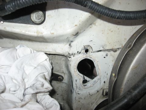 1994 Ford Bronco - Close-up view of a vehicle's engine bay firewall, showing a hole and a white cloth covering part of the area.