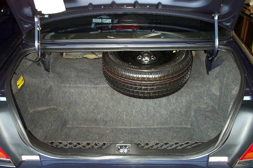 Open car trunk showing carpeted floor and full-size spare tire