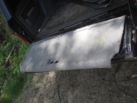 1993 Ford Bronco - The interior panel of a vehicle has been removed, revealing the carpeted cargo area and surrounding frame.
