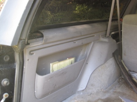 1993 Ford Bronco - The interior of a vehicle shows a gray plastic panel with a built-in storage pocket.