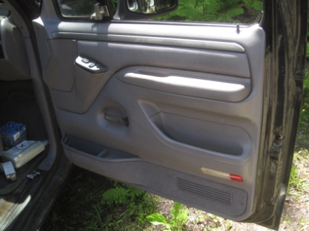 1993 Ford Bronco - The interior door panel of a vehicle is shown, with visible storage compartments and window controls.