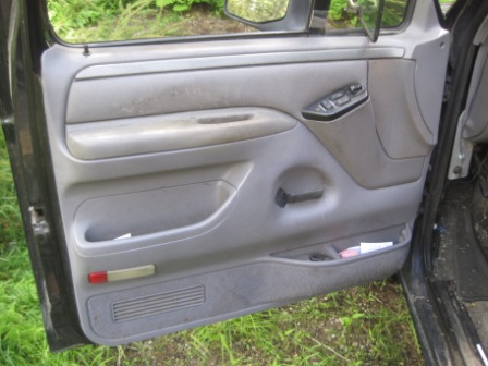 1993 Ford Bronco - The interior of a truck's driver side door is shown, with visible storage compartments and controls.