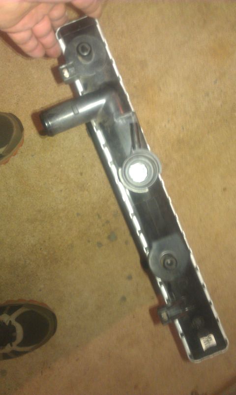 1991 Ford Festiva - A car radiator part is shown, with a hand holding it above a floor.