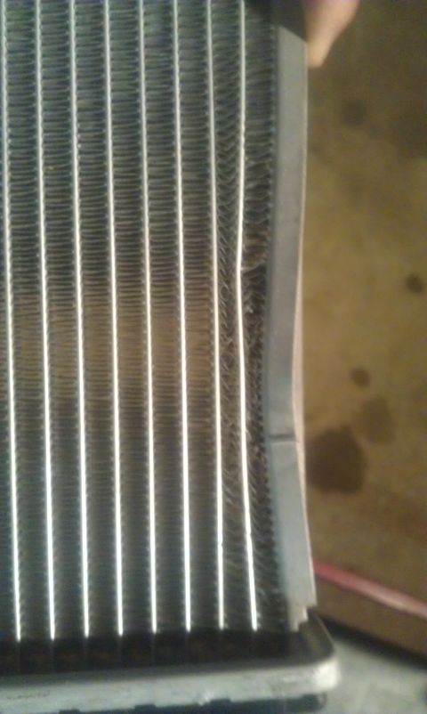 1991 Ford Festiva - This image shows a close-up of a car's radiator, highlighting its fins and some visible damage.