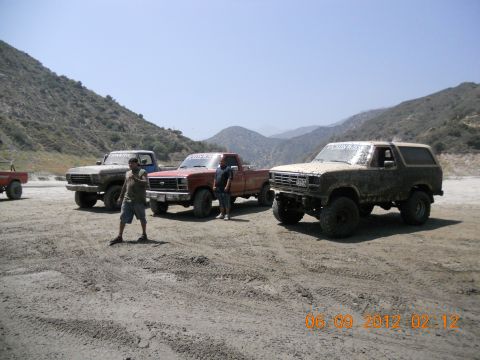 1986 Ford Bronco - Three trucks and a Bronco are parked in a dry, mountainous area.