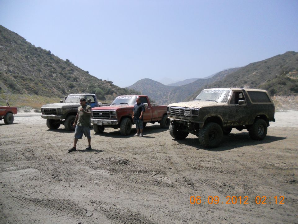 Tan Ford Bronco with aftermarket wheels and tires, parked on dirt