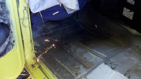 1978 Ford Bronco - Welding sparks are visible inside the floor pan of a vehicle during repairs.