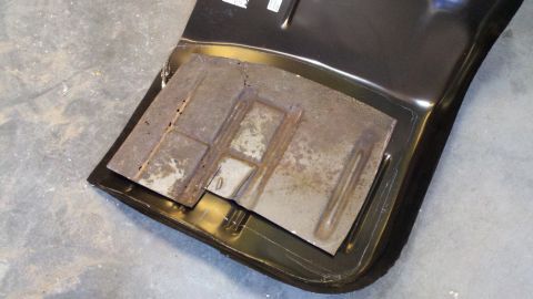 1978 Ford Bronco - A close-up view of a rusted metal panel with stamped reinforcement lines and squares.