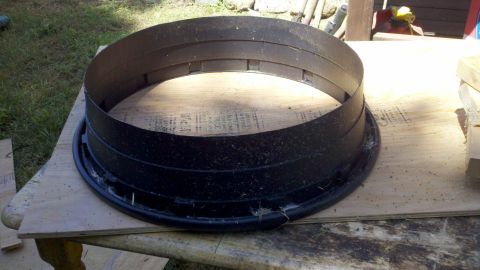 1978 Ford Bronco - A black fan shroud is shown resting on a piece of plywood outdoors.