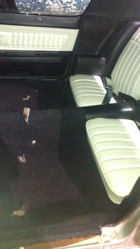1973 Chevrolet Camaro - The interior of a car shows white bucket seats and black carpeting, with a portion of the door panel visible.