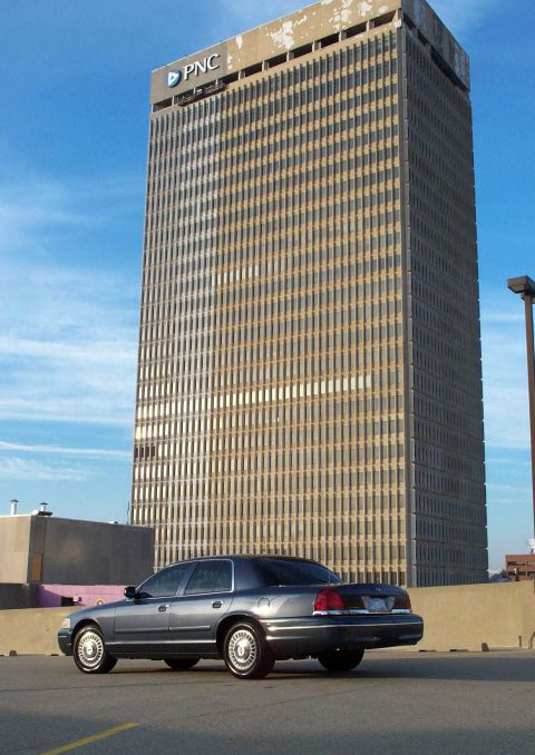1998 Ford Crown Victoria - Rear view of a 1998 Ford Crown Victoria parked outdoors with a large building behind it.