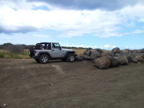 1990 Chevrolet Suburban - A silver Jeep Wrangler is parked on a dirt path next to a large rock formation.