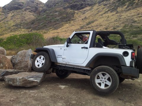 1990 Chevrolet Suburban - Jeep Wrangler navigating rocky terrain off-road.