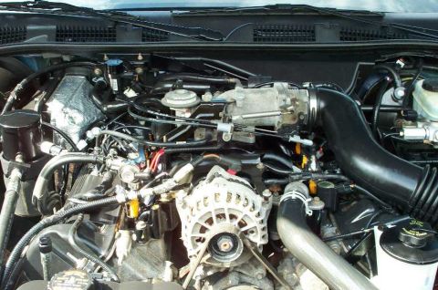 1998 Ford Crown Victoria - Close-up view of a vehicle's engine bay, showing the alternator, intake manifold, and various hoses and wires.