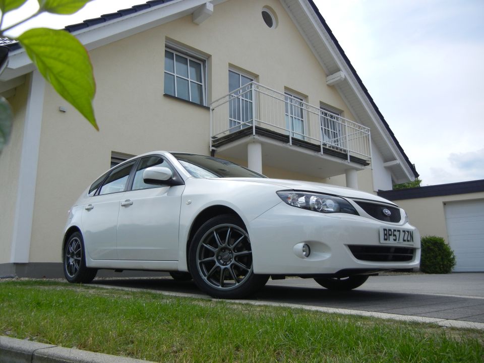 White 2008 Subaru Impreza hatchback parked in front of a house