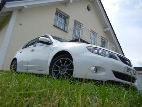 2008 Subaru Impreza - White 2008 Subaru Impreza hatchback with aftermarket wheels parked on lawn.
