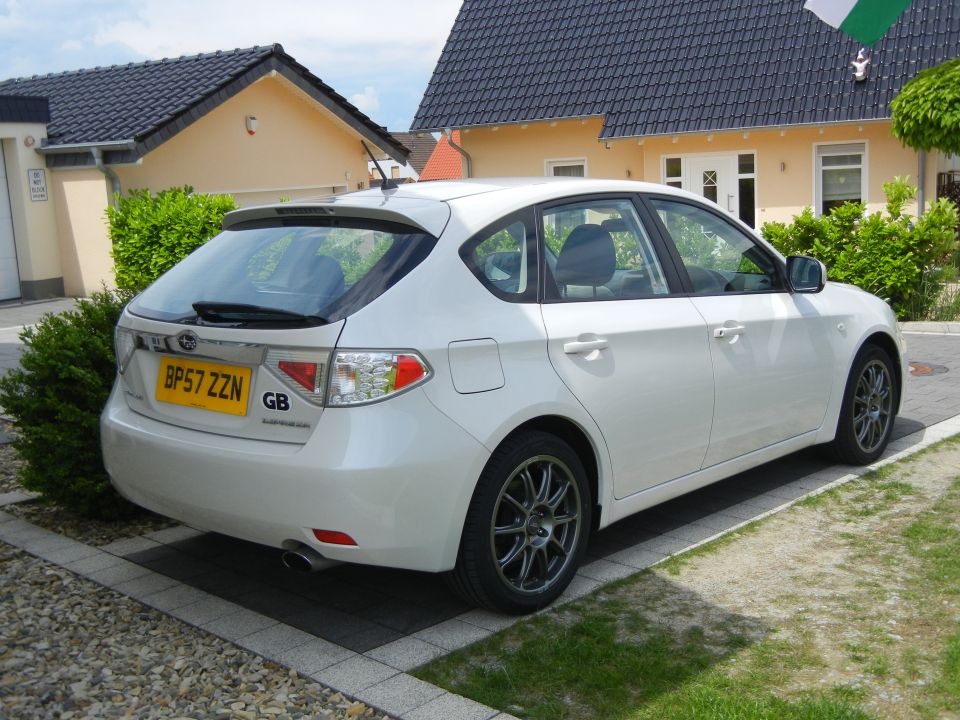 White 2008 Subaru Impreza hatchback parked in front of a house