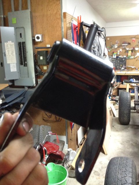 1986 Ford Bronco - A black metal bracket is held in front of a garage scene that includes an electrical panel and tires.