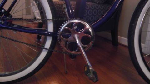 1953 Ford Mainline - Detail shot of a bicycle's drivetrain, including the crankset, chain, and wheels with white sidewall tires.