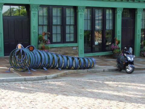 2008 Yamaha Zuma - A unique sculpture resembling a caterpillar sits next to a parked scooter outside a building.