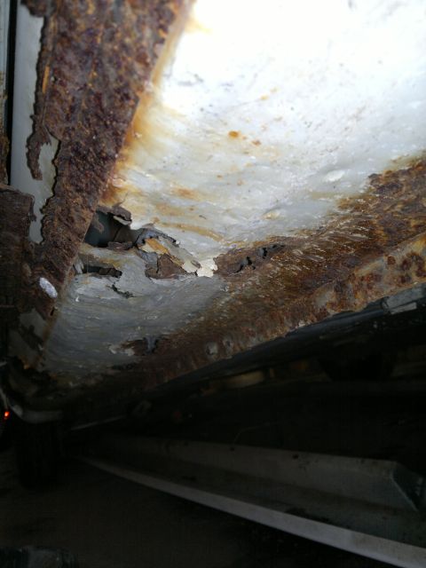 1993 Ford Taurus - Extensive rust and deterioration are visible on the vehicle's undercarriage, indicating significant structural compromise.