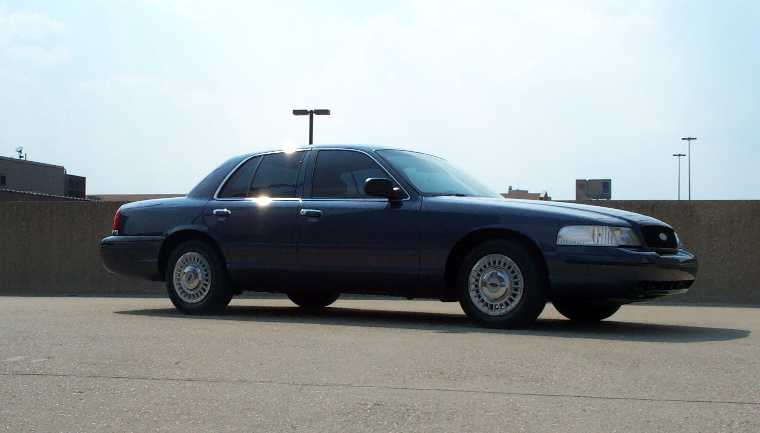 Dark blue Ford Crown Victoria sedan, passenger side view, parked on rooftop lot