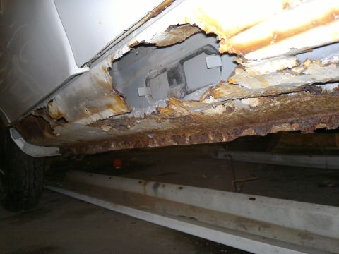 1993 Ford Taurus - The rocker panel on this vehicle shows extensive rust and deterioration, compromising its structural integrity.