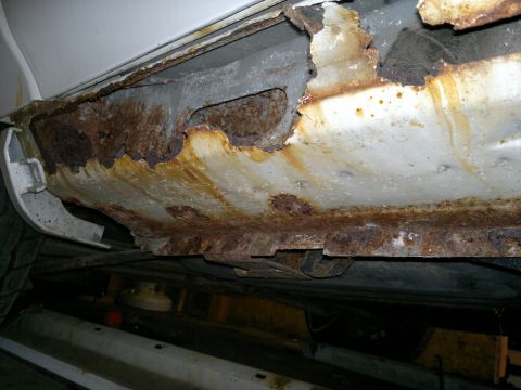 1993 Ford Taurus - Severe rust damage is visible on the rocker panel and structural components of the vehicle.