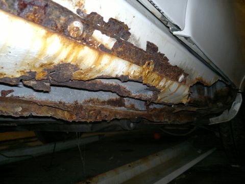 1993 Ford Taurus - Severe rust damage is visible on the rocker panel and structural components of the vehicle.