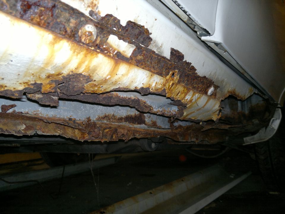 Close-up of heavily rusted car rocker panel and undercarriage