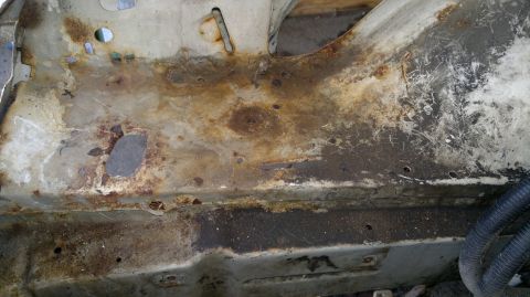 1993 Ford Taurus - Extensive rust damage is visible on the vehicle's metal frame, with several holes and some wiring present.