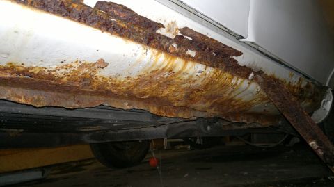 1993 Ford Taurus - The rocker panel of a vehicle shows extensive rust damage and deterioration.