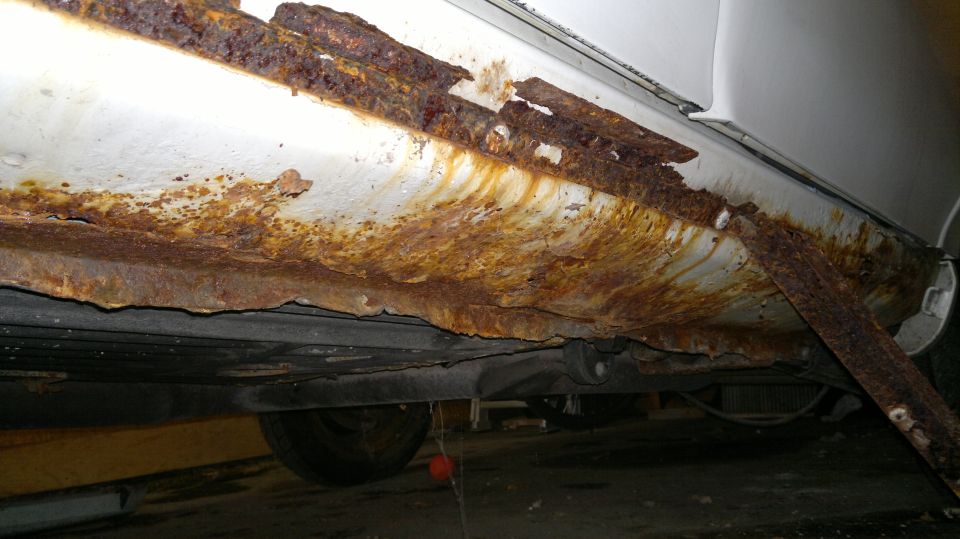 Car's lower body panel is heavily rusted and flaking off