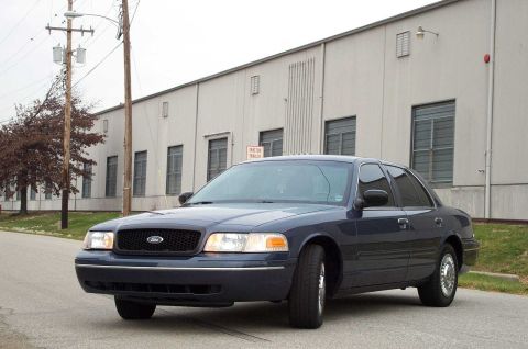 1998 Ford Crown Victoria - Dark blue 1998 Ford Crown Victoria sedan parked on a street with a building in the background.