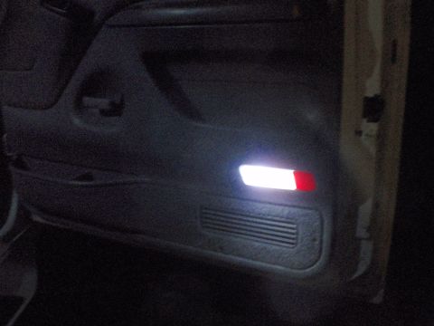 1995 Ford Bronco - Close-up of a vehicle's interior door panel, showing illuminated lights and a speaker grille.